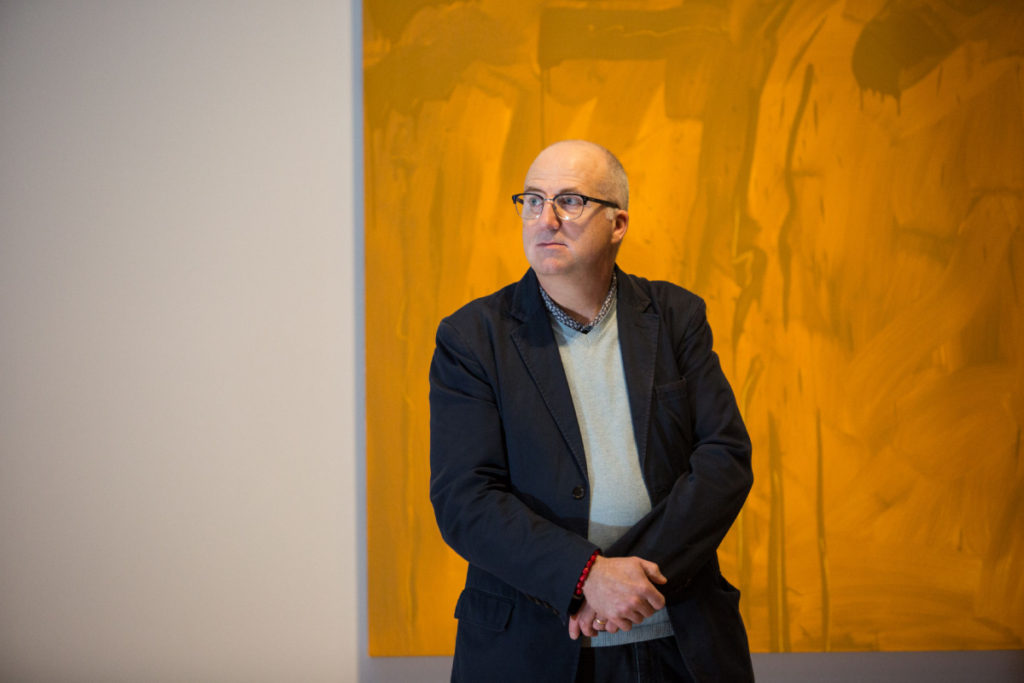 Andrew Hunter, curator at the Art Gallery of Ontario, behind him is a painting by Robert Houle called Premises for Self Rule: Constitution Act, 1982__1994, Oil on canvas, photo emulsion on canvas, laser-cut vinyl, at the Art Gallery of Ontario. Toronto, Ontario. December 30, 2015. Nick Kozak/For the Toronto Star.